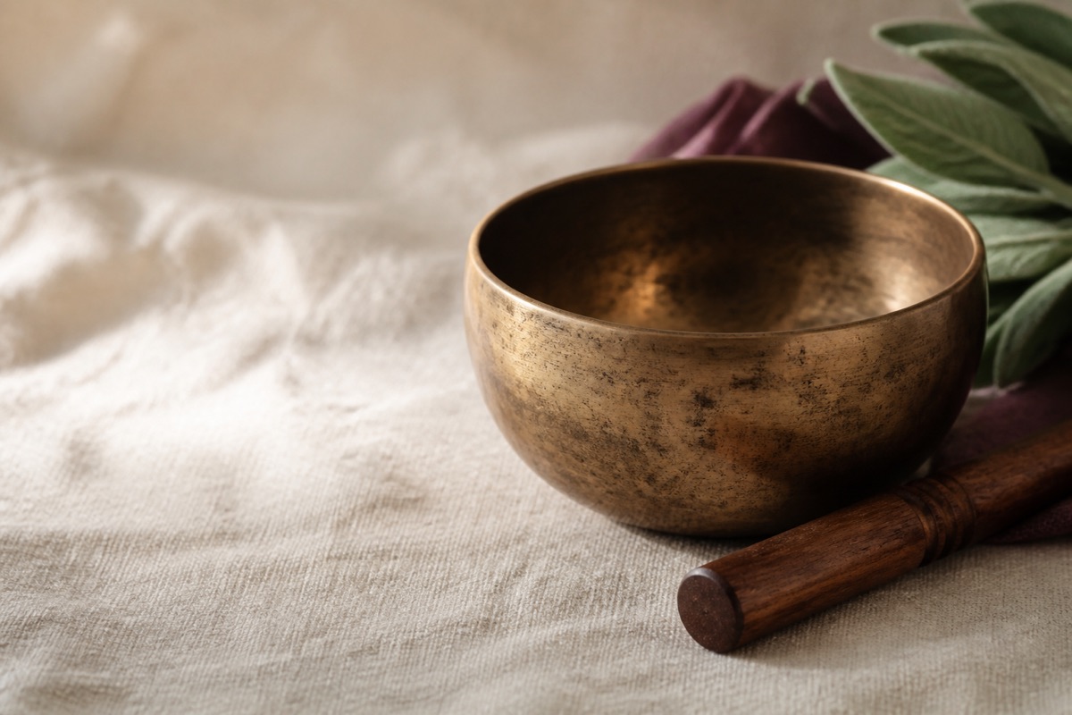 Dettaglio di una campana tibetana con battente su un tessuto chiaro